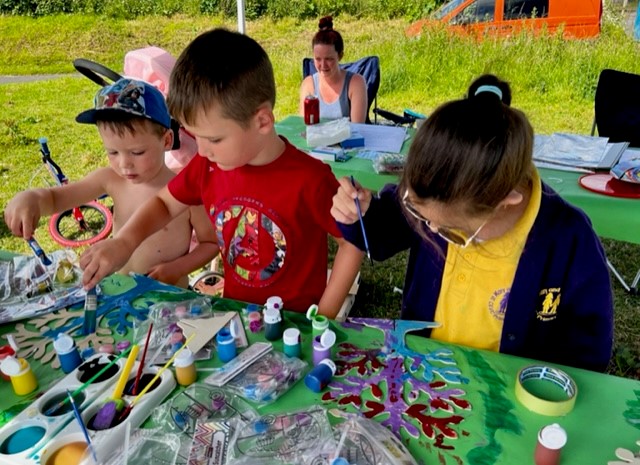 Three young people painting at a craft table at Chubbards Cross site