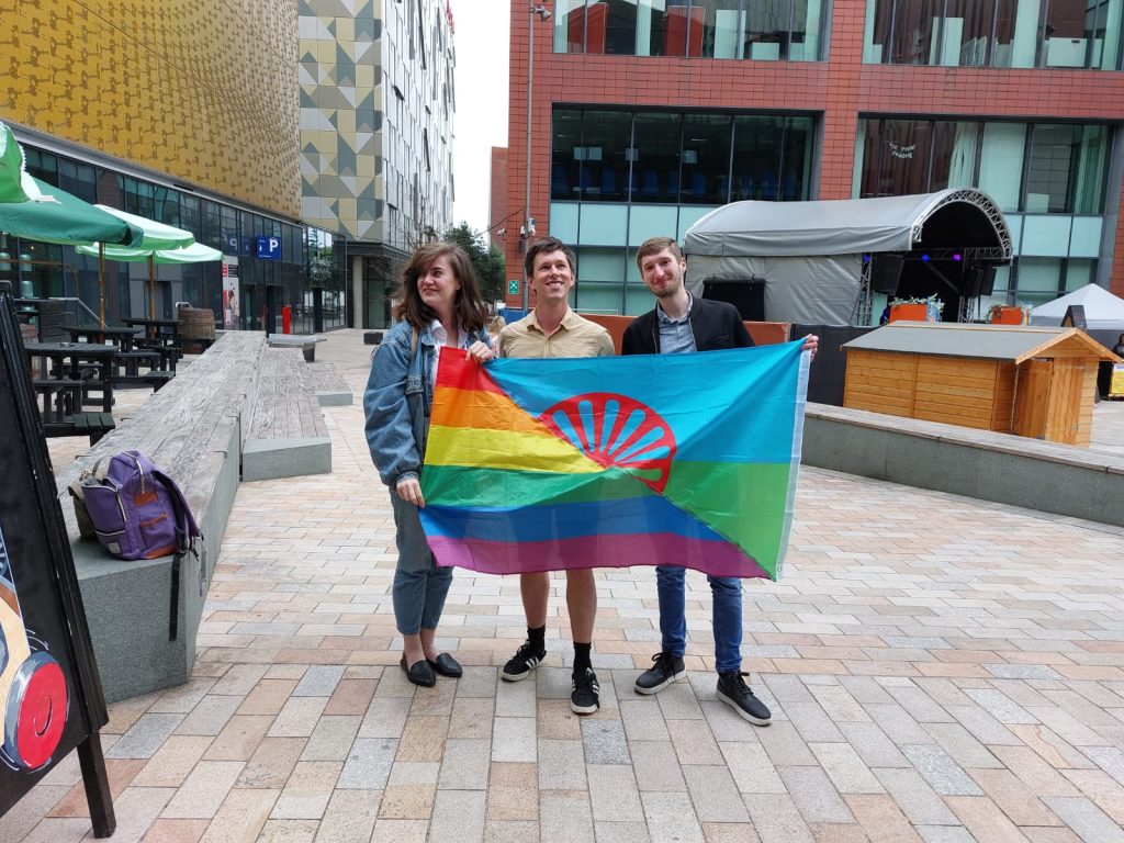 Tyler Hatwell (centre) with two Traveller Pride members holding a Romani and LGBTQ+ pride flag